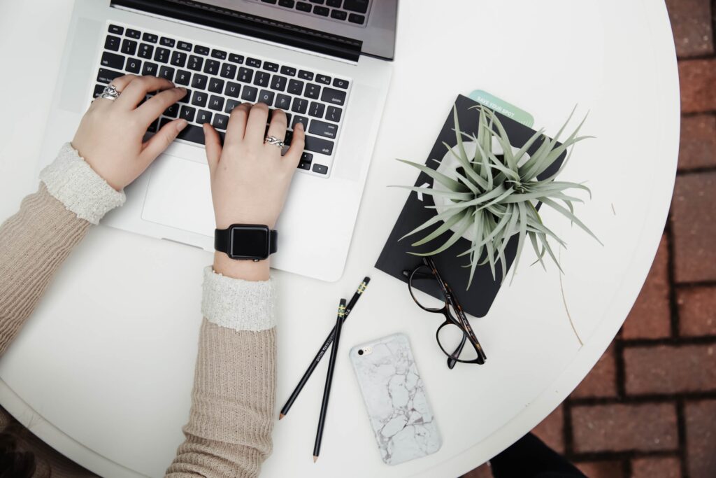 Person working on a laptop beside a plant